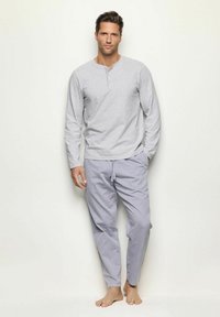 Camisa de manga larga gris con cuello henley, combinada con pantalones de pijama rayados en azul y blanco. La tela parece suave y ligera.
