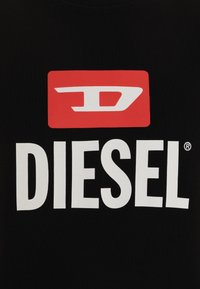 Tessuto di cotone nero con un grande rettangolo rosso che presenta una "D" stilizzata bianca sopra il testo bianco "DIESEL" in grassetto.