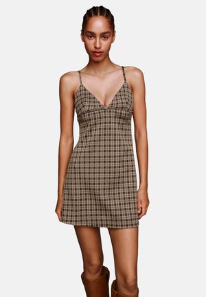 Braun kariertes Minikleid mit dünnen Trägern und V-Ausschnitt. Das Material scheint leicht zu sein, mit einem figurbetonten Oberteil und einem ausladenden Rock.