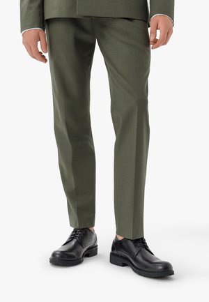Czarne sznurowane buty z okrągłym noskiem, noszone z oliwkowymi, fakturowanymi spodniami. Formalny design charakteryzuje się gładką skórą i solidną podeszwą.