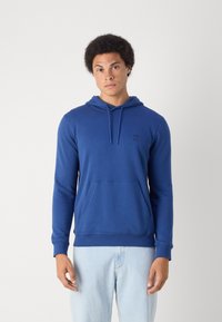 Felpa con cappuccio blu in morbido tessuto, dotata di una tasca a marsupio anteriore, polsini a costine e un piccolo badge logo sul petto.