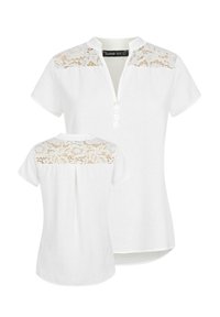 Camicia bianca a maniche corte con un design in pizzo sulle spalle e sulla schiena, con collo a bottoni e un orlo leggermente curvato.
