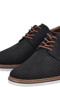 Schwarze Netzschnürschuhe mit braunen Schnürsenkeln, die ein gewebtes Oberdesign, glatte Akzente und eine weiße Gummisohle mit einem sandfarbenen Rand aufweisen.