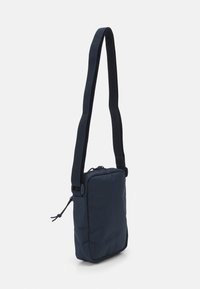 Borsa a tracolla blu navy con forma rettangolare, realizzata in tessuto resistente, dotata di chiusura con zip e tracolla regolabile. Texture liscia.