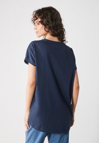 Navy blue short-sleeve t-shirt made of cotton with a round neckline and a relaxed fit. Smooth texture, slightly curved hem at the back.