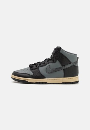 Høj top sneaker i sort og gråt læder med sorte snørebånd og beige sål, vist i sideprofil på hvid baggrund.