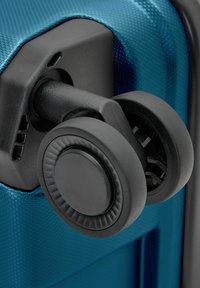 Nahaufnahme von zwei schwarzen Spinner-Rädern, die an einer strukturierten blauen Hartschalenkoffer-Ecke befestigt sind.