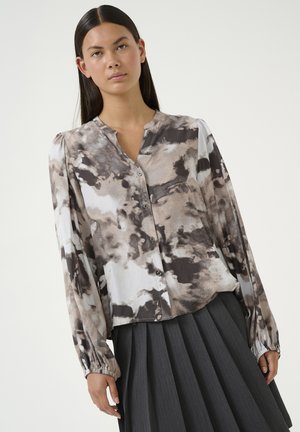 Blusa de manga larga en una mezcla de patrones abstractos en gris, negro y beige. Presenta una tapeta frontal abotonada y puños elásticos.