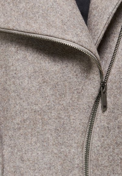 Chaqueta de lana gris con cremallera diagonal, tejido texturizado y diseño de cuello chal. El detalle de la cremallera incluye un tirador de metal.