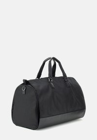 Borsa duffel nera realizzata in tessuto testurizzato con base in pelle liscia, forma rotonda, due manici superiori e chiusura con zip.