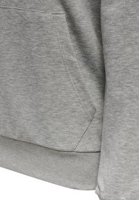 Sweat-shirt gris avec une finition texturée, comprenant une poche kangourou et un ourlet côtelé. Le tissu semble doux et lég èrement brossé.