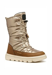 Bota metálica dorada, hasta la mitad de la pantorrilla, con parte superior acolchada, cordones beige y un acento de cuero marrón. Cuenta con una suela texturizada y un tacón de goma.