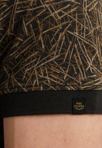 Sort shorts med et struktureret mønster af brune og beige linjer. Har en sort talje og en lille sort label med "PME Legend."
