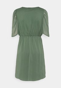 Robe verte à manches courtes avec une taille froncée, présentant un tissu lisse et fluide avec une légère brillance. Vue de dos montrant une coupe décontractée et un col arrondi.