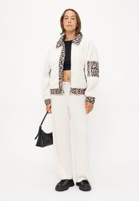 Badjas van fleece met een kraag en manchetten in luipaardprint, crèmekleurig lijf, gecombineerd met crèmekleurige wijde broek en zwarte chunky schoenen.