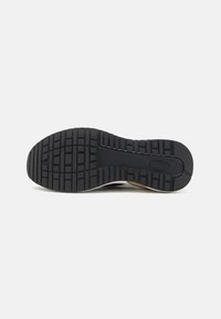Semelle de chaussure en caoutchouc noir avec un motif de traction texturé, comprenant des rainures profondes et des sections surélevées pour une meilleure accroche. Les bords lisses se fondent dans la tige.