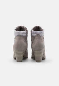 Botas ankle taupe con un acabado de ante suave, cuello de tela a rayas, cremallera lateral y tacón apilado en forma cónica.