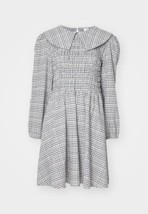 Robe smockée à manches longues, col rond, motif à carreaux gris et blancs, tissu léger, et taille froncée pour une silhouette évasée.