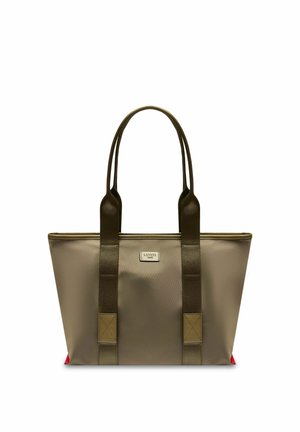 Sac fourre-tout taupe avec des poignées marron foncé et une petite étiquette rectangulaire sur le devant, avec des accents rouges aux coins inférieurs.