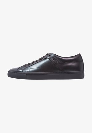 Zapatillas negras de cuero con un acabado liso, puntera redonda y cordones del mismo tono. Presentan suela de goma de perfil bajo y logotipo en relieve en el lateral.