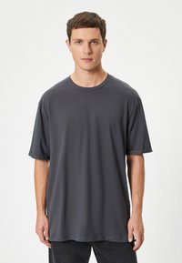 Mørkegrå kortærmet t-shirt med rund hals, lavet af blødt bomuldsstof. Har en afslappet pasform og opfoldede ærmer.