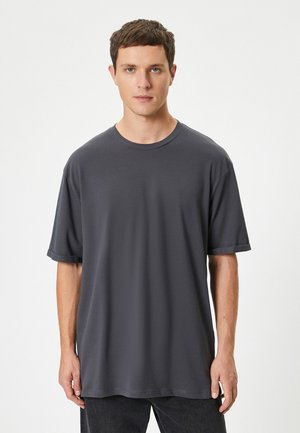 Mørkegrå kortærmet t-shirt med rund hals, lavet af blødt bomuldsstof. Har en afslappet pasform og opfoldede ærmer.
