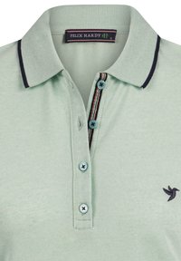Lichtgroen poloshirt met een donkerblauwe kraag, drie knopen en kleurrijke gestreepte accenten. Beschikt over een geborduurd vogel-logo op de borst.
