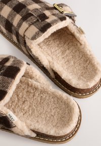 Barna és bézs kockás szövetpapucs puha, műszőrme béléssel, oldalsó csattal és masszív tapadós talppal.