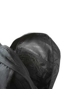 Mochila negra con un exterior texturizado; cuenta con un compartimento principal con cremallera, forro con logo y bolsillos internos para la organización.