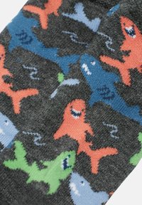 Calcetines negros con un patrón divertido de tiburones coloridos en rojo, verde, azul y azul claro, acompañados de ondas suaves. Textura de tela suave.