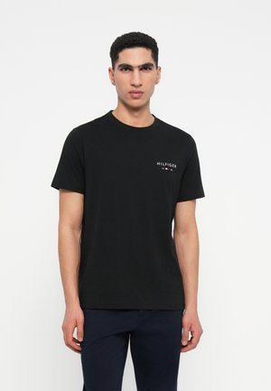 Čierne tričko s krátkymi rukávmi vyrobené z bavlny s okrúhlym výstrihom a malou bielou logom na ľavej strane hrude. Hladká textura.