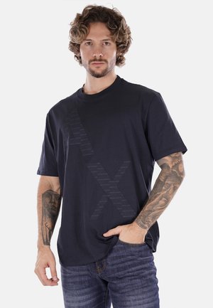 Camiseta de algodón azul marino con un gran diseño impreso de "AX" en la parte delantera, mangas cortas y cuello redondo.