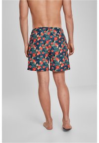Pantaloni scurți de înot pentru bărbați cu un fundal bleumarin și modele florale vibrante în roșu, roz și verde. Talie elastică, lungime deasupra genunchilor.