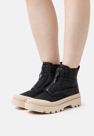 Botines negros hasta el tobillo con textura acolchada, cierre de cremallera y suela de goma gruesa color crema. Presenta una puntera redonda y un mediopie acanalado.