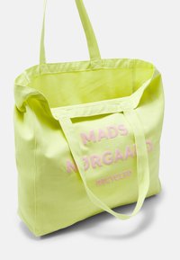 Sac fourre-tout vert clair avec de longues poignées, portant le texte rose "MADS NØRGAARD RECYCLED" à l'avant, se tenant droit sur fond blanc.