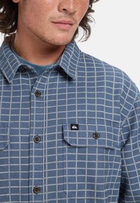 Blauw geruit flanellen shirt met een wit rasterpatroon, button-down kraag, twee borstzakken en een klein logo op de zak.