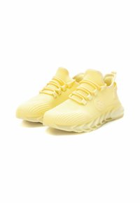 Zapatillas deportivas de color amarillo claro con parte superior de malla, diseño texturizado y suela acolchada. Presenta cordones y logo en el lateral.