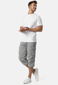 Witte katoenen t-shirt gecombineerd met lichtgrijze cargoshorts, met meerdere zakken en een ontspannen pasvorm. Witte sneakers maken de look af.