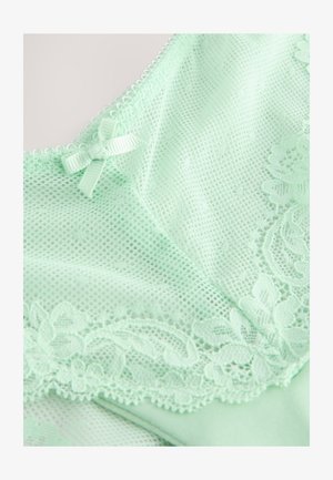 Mündirohelist pesu, millel on peen pitsääris, võrgust tekstuur ja väike satiinnööp kaelusel.