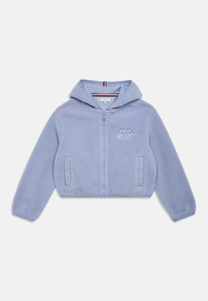 Hellblauer, flauschiger Zip-Hoodie mit zwei Fronttaschen und kleinem, gesticktem Herzlogo auf der Brust.