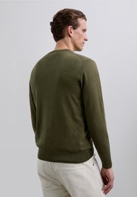 Sweter w kolorze oliwkowej zieleni z długimi rękawami i okrągłym dekoltem, wykonany z miękkiego materiału, charakteryzujący się gładką fakturą i prążkowanym wykończeniem na dole.