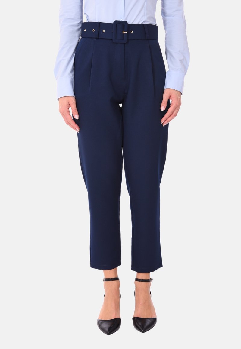Pantaloni sartoriali blu navy con una larga cintura e fibbia, caratterizzati da pieghe e lunghezza cropped, abbinati a décolleté nere a punta.