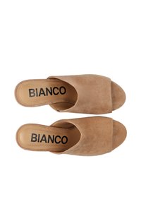 Mule in suede beige senza lacci con punta aperta, ampia fascetta anteriore e soletta imbottita. Stampe "BIANCO" in lettere nere in grassetto sulla soletta.