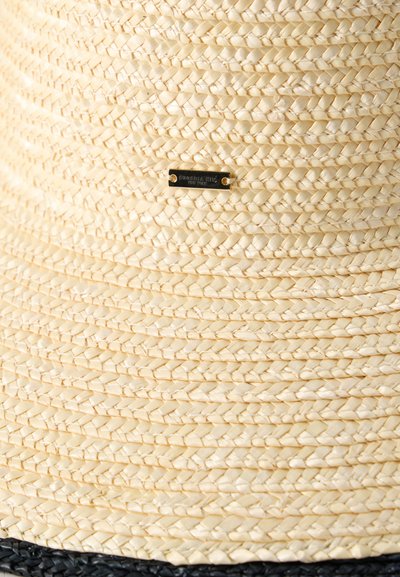 Ψάθινο καπέλο με υφαντή μπεζ υφή, διαθέτει μαύρη κορδέλα και μεταλλική ετικέτα χαραγμένη με "Eugenia Kim New York".
