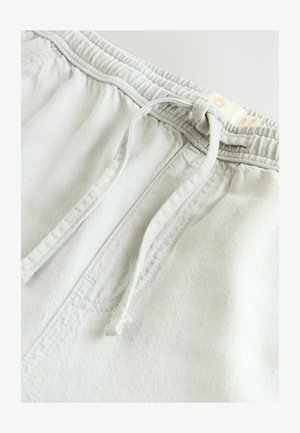 Svetlo sivi trening hlače s elastičnim pasom, vezalko in sprednjim žepom, narejene iz mehkega denima z gladko teksturo.