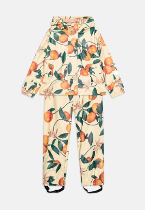 Giacca e pantaloni da pioggia in materiale lucido e leggero con un motivo di arance e foglie su sfondo crema. Presentano un cappuccio e polsini regolabili.