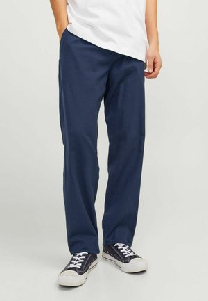 Pantalons en coton léger bleu marine avec une coupe droite, un front plat, des poches latérales et une texture subtile. Associés à des baskets noires.