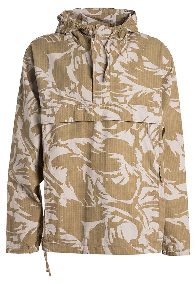 Beige anorak med vitt abstrakt mönster, långa ärmar, huva och en framficka. Tillverkad av lätt, texturerad tyg.