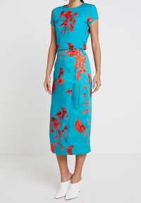 Abito turchese con stampa floreale rossa, maniche corte, dettaglio in vita e lunghezza midi. Presenta una silhouette dritta e una texture liscia.