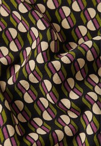 Tessuto con un motivo ripetuto di forme color crema con strisce viola e verdi su uno sfondo nero, texture intrecciata.